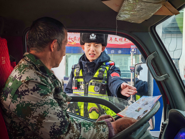 图为检查站民警对边民进行反诈宣传