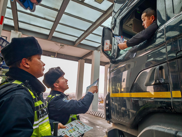 图为检查站民警对外贸司机进行反诈宣传